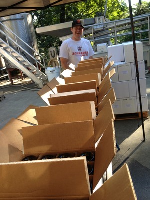 man standing at the end of a conveyor belt of cases of wine