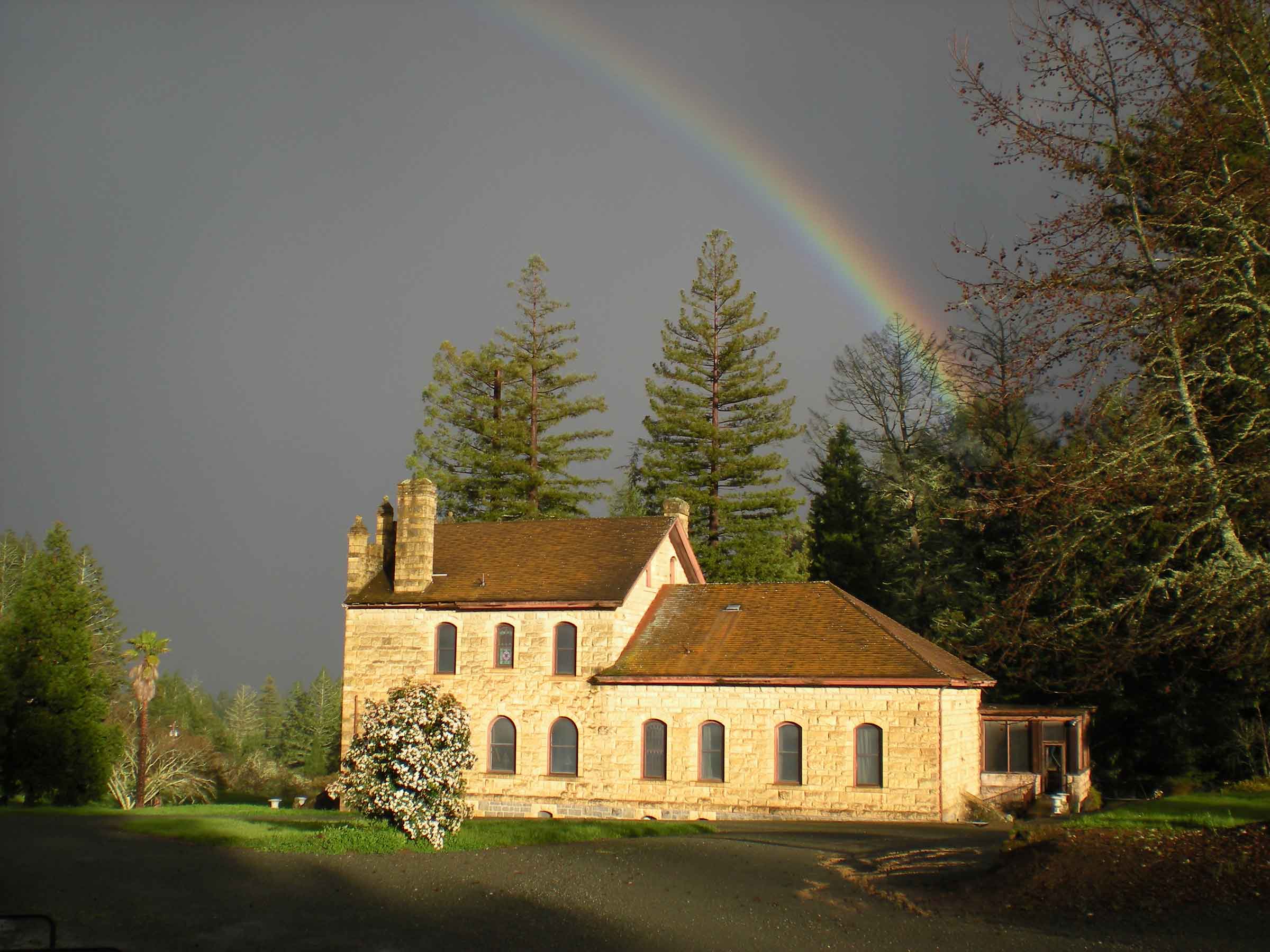 a rainbow over the Wallis Estate chateau against a gray sky