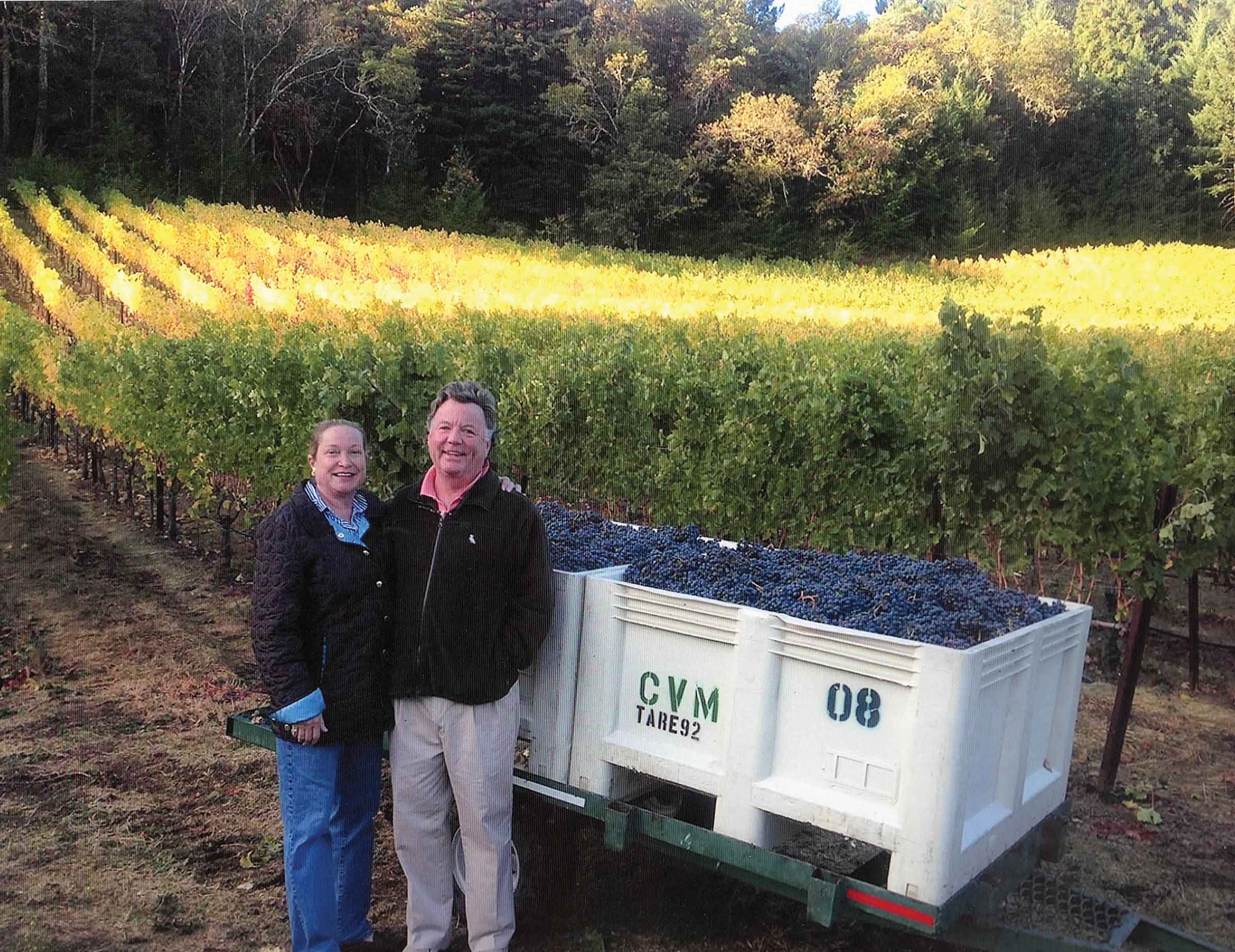 Marilyn and Edward Wallis standing in front of bins in the vineyard